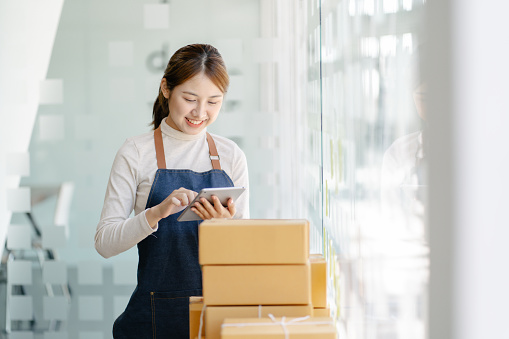 Freelance business woman smiling happy to check the stock of products that are ready to be shipped to customers according to their orders.