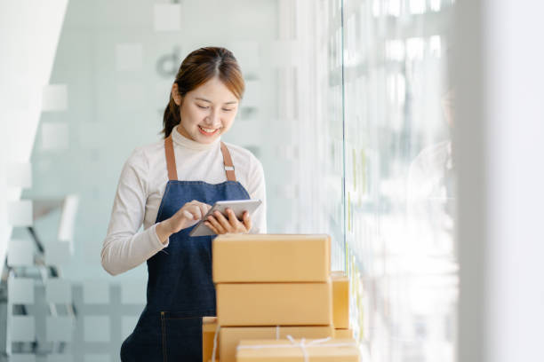 Freelance business woman smiling happy to check the stock of products that are ready to be shipped to customers according to their orders. Freelance business woman smiling happy to check the stock of products that are ready to be shipped to customers according to their orders. market trader stock pictures, royalty-free photos & images