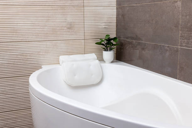 Baño de color beige pastel con bañera y almohada blancas y paredes de mármol - foto de stock