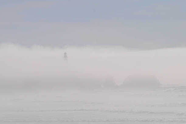 Lighthouse silhouetted through fog bank