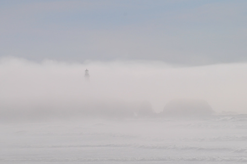 Lighthouse silhouetted through fog bank