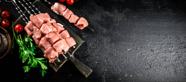 istock Pork kebab raw on a cutting board with tomatoes and parsley. 1368321469