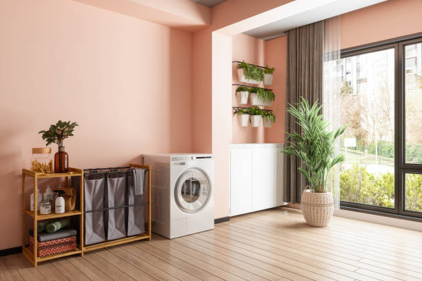 interno della lavanderia con lavatrice asciugatrice, cesto della biancheria, piante in vaso e parete color corallo - ripostiglio camera foto e immagini stock