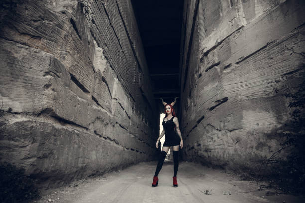 woman with red hair, huge devil horns decorates her head. Portrait of the beautiful young woman in devil carnival shape