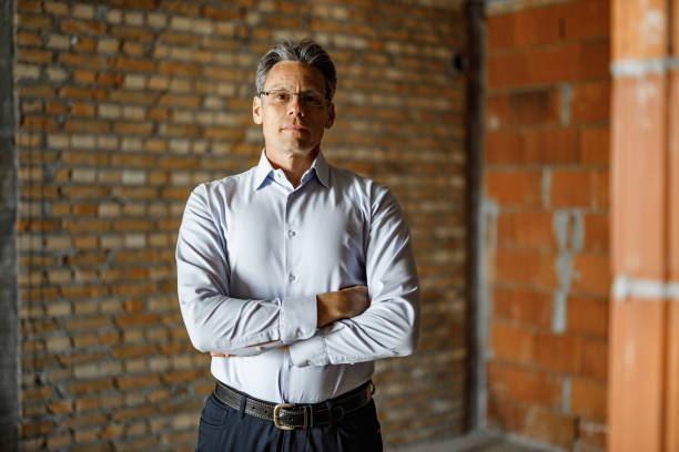 istock Confident male architect with crossed arms at construction site. 1368328742