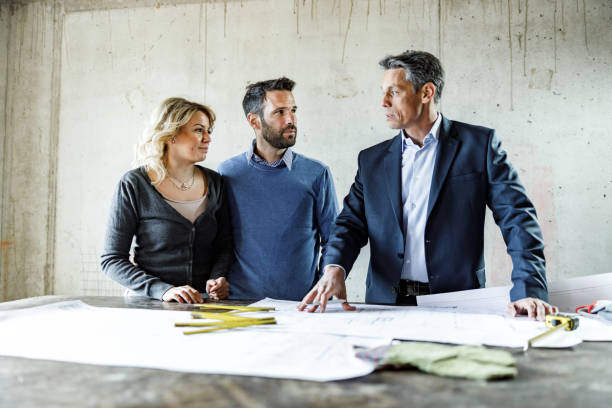 istock Couple talking to architect about blueprints at construction site. 1368329452