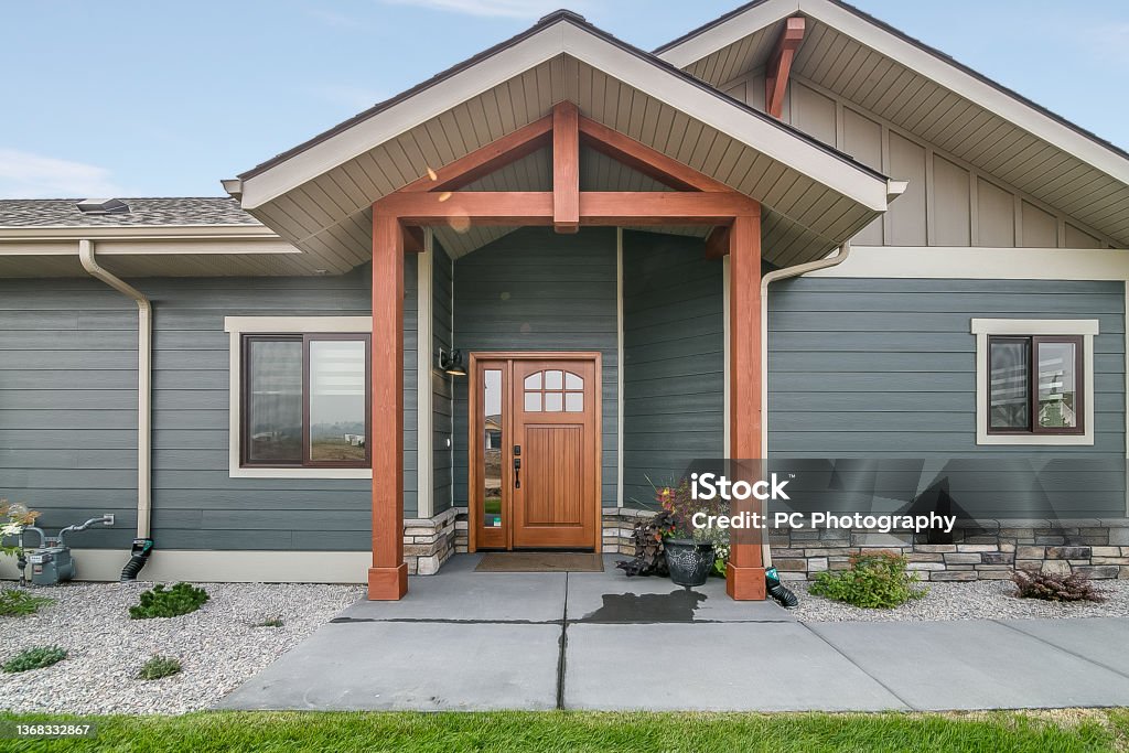 New build with blue and brown exterior Stained wood front door and columns House Stock Photo
