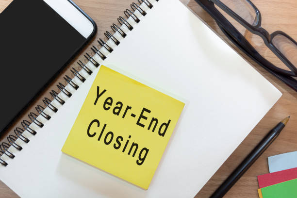 Text on yellow note with notepad on wooden desk - Year-end closing stock photo