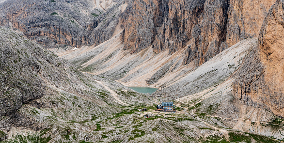 Rifugio Antermoia and Lago di Antermoia with steep rocks around from Mantel hill summit in DOlomites mountains in Italy