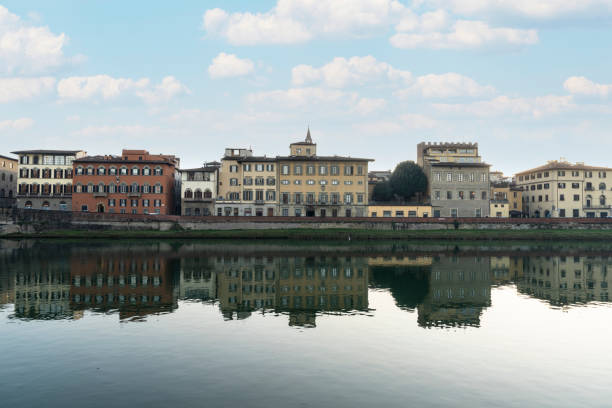 A scenic view of the buildings along the Arno River in Florence. The contrasting colors of the architecture stand out against the backdrop of the river, with a soft, natural light enhancing the peaceful atmosphere. The mix of modern and traditional buildings reflects the unique blend of history and contemporary life in Florence.
