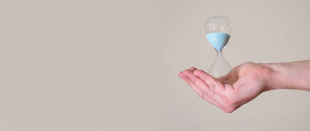istock Hourglass in the hands of a man on a light background. 1368344756