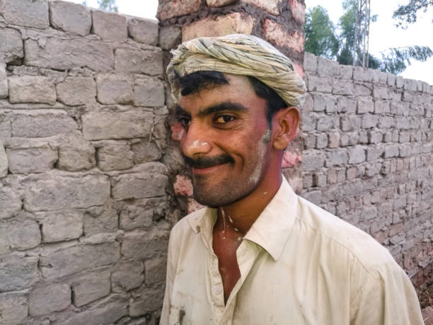an asian poor labor is working on the site and smiling and his has crossed eyes