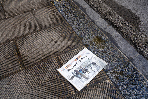 Florence, Italy. January 2022. a copy of the New York Times newspaper lying on the ground on a downtown sidewalk
