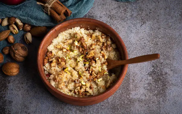 Sweet couscous with honey and nuts in a brown bowl on a dark rustic background. French dessert.