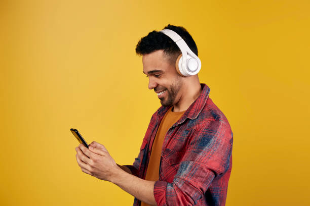 istock Content ethnic man in headphones browsing smartphone 1368349309