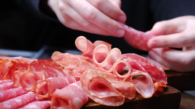 Human hands are serving meat plate, Italian antipasto