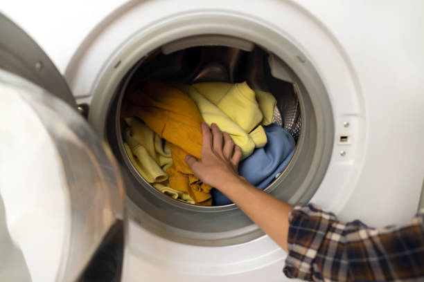 istock Woman puts bright clothes into a washing machine. 1368352320