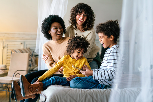 Family happiness children gay parents concept. Happy multiethnic women couple having fun with kids at home