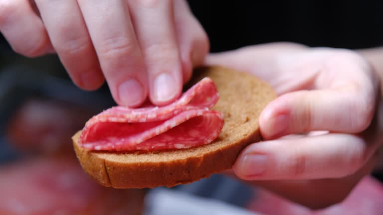 Human hands are taking a slice of salami from meat plate, Italian antipasto