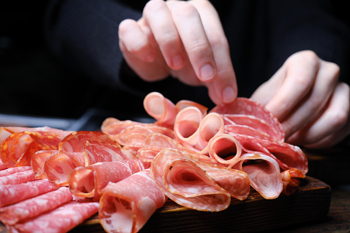 Human hands are serving meat plate (tagliere di salumi), Italian antipasto