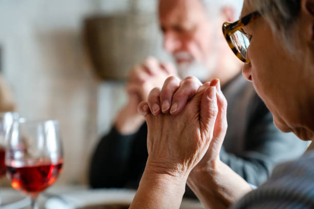 Christian senior couple praying at table worshipping the Lord Christian senior couple praying at table worshipping the Lord at home old couple praying stock pictures, royalty-free photos & images