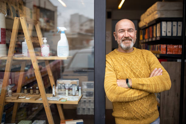 orgulloso propietario de pie con los brazos cruzados frente a su tienda - pensionistas trabajadores fotografías e imágenes de stock