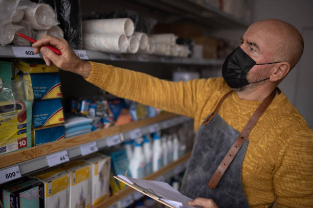istock Mature male small business owner doing inventory at retail store, while wearing protective face mask 1368355099