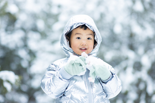Little boy holding snowball in winter