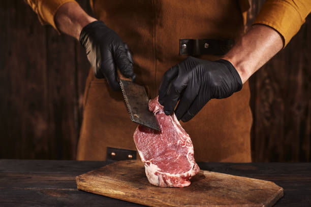 istock The butcher cuts the meat with gloves. 1368360812