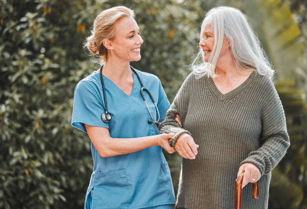 scatto di un'infermiera che prende aria fresca con il suo paziente anziano - senior adult nursing home assisted living talking foto e immagini stock