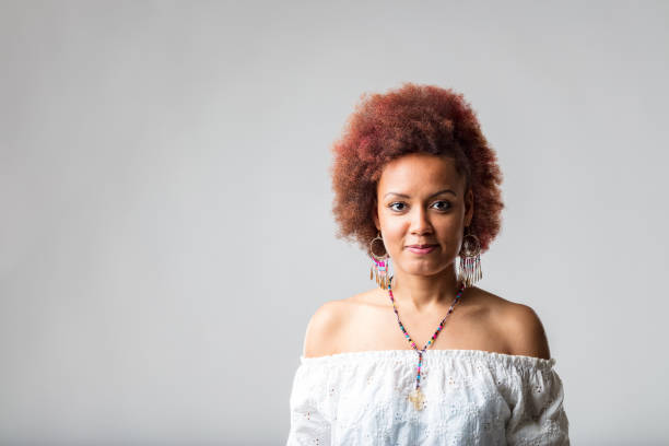 Stylish young Black woman with an impish grin posing over white with copyspace