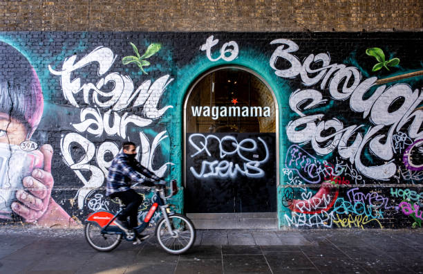 Wall Art Or Graffiti Outside Wagamama Restaurant Southwark London England UK, 29 January 2022, Wall Art Or Graffiti Outside Wagamama Restaurant Southwark Bankside With A Man On Bicycle Passing bankside photos stock pictures, royalty-free photos & images