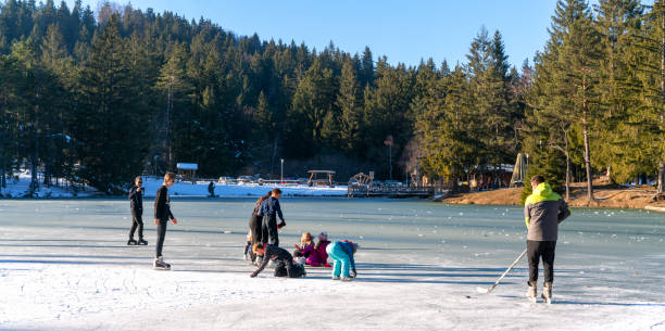 un grupo de jóvenes juega, practica hokey y disfruta del congelado lake bloke en el centro de eslovenia. - winter lake snow notranjska fotografías e imágenes de stock