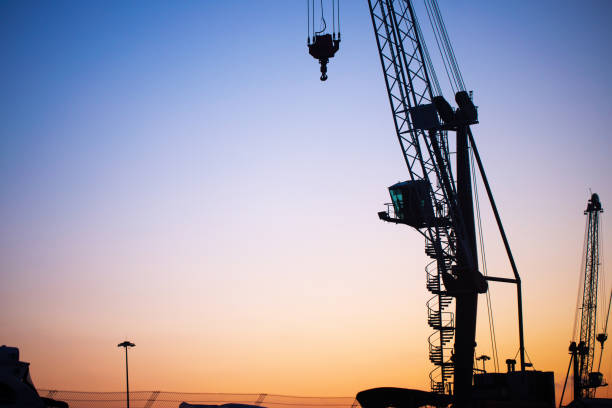 istock Silhouette of a crane at a cargo port at sunset 1368366592