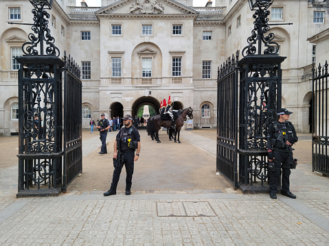 Changing the guard at Horseguards parade, Whitehall, London, England, UK, The guards are on horseback and in ceremonial outfits but are all serving soldiers in the British army.  In the foreground are armed policemen.