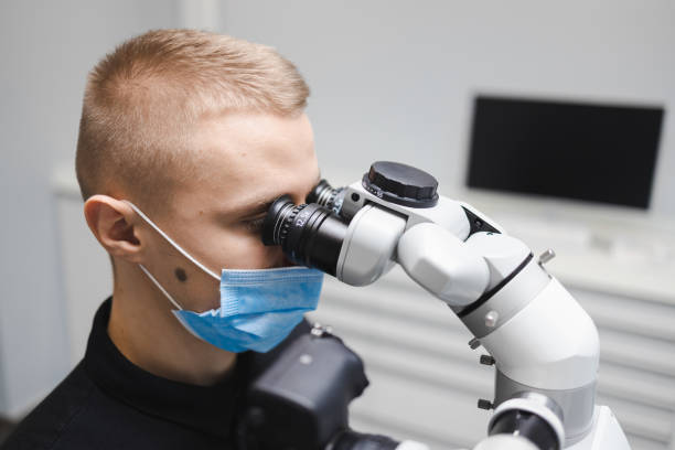 istock Male dentist doctor using microscope for dental treatment 1368368383