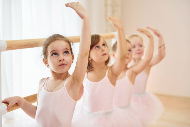 маленькие балерины готовятся к выступлению, отрабатывая танцевальные движения - little girls group of people happiness cheerful стоковые фото и изображения
