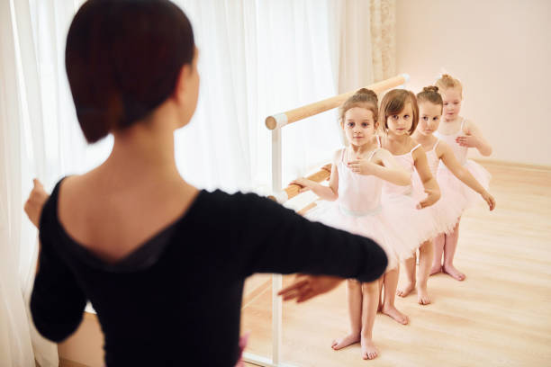 istock Coach teaches children. Little ballerinas preparing for performance by practicing dance moves 1368370084