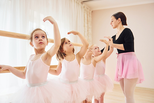Woman teaches dance moves. Little ballerinas preparing for performance.