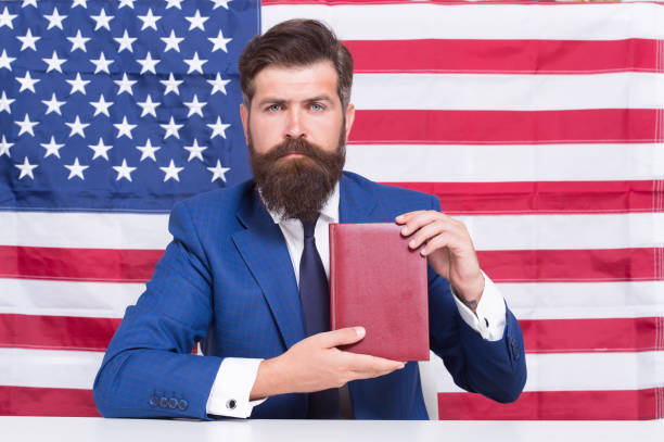 Liberty of printing. Patriotic businessman hold book on american flag blackground. American liberty. Independence day. 4th of July. Pride and liberty. Political rights and freedoms. Liberty of choice. libertad de impresión. empresario patriótico sostiene libro sobre el suelo negro de la bandera estadounidense. libertad americana. día de la independencia. 4 de julio. orgullo y libertad. derechos y libertades políticas. libertad de elección