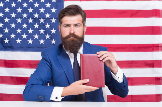 印刷の自由。愛国的な実業家は、アメリカの旗のブラックグラウンドに本を保持します。アメリカの自由。独立記念日。7月4日。誇りと自由。政治的権利と自由。自由な選択 - freedoms ストックフォトと画像