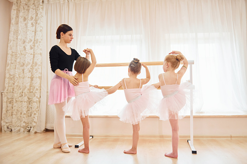 Little ballerinas preparing for performance by practicing dance moves.