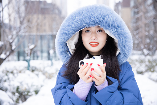 Young women holding a hot cup coffee in winter