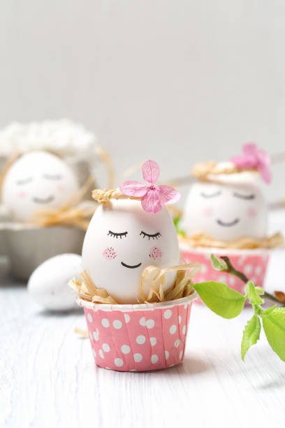 istock Easter holiday concept with cute handmade white eggs, tree branches, quail feathers and spring flowers on white wooden background. 1368371801