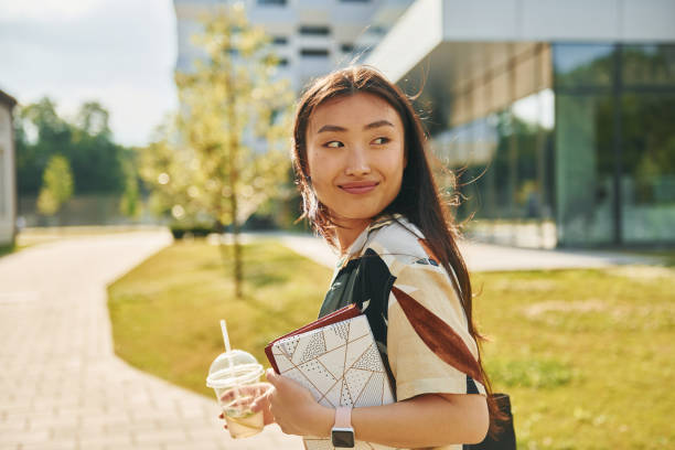 istock With drink. Young asian woman is outdoors at daytime 1368378017