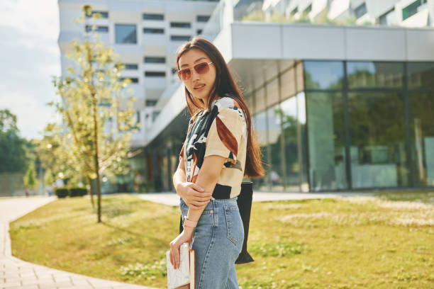istock With notepad in hands. Young asian woman is outdoors at daytime 1368378067