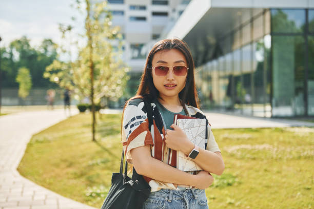 istock With notepad in hands. Young asian woman is outdoors at daytime 1368378089