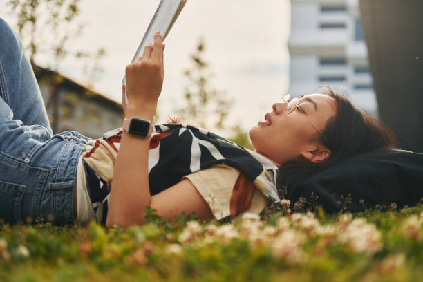 istock Lying on the grass. Young asian woman is outdoors at daytime 1368378943
