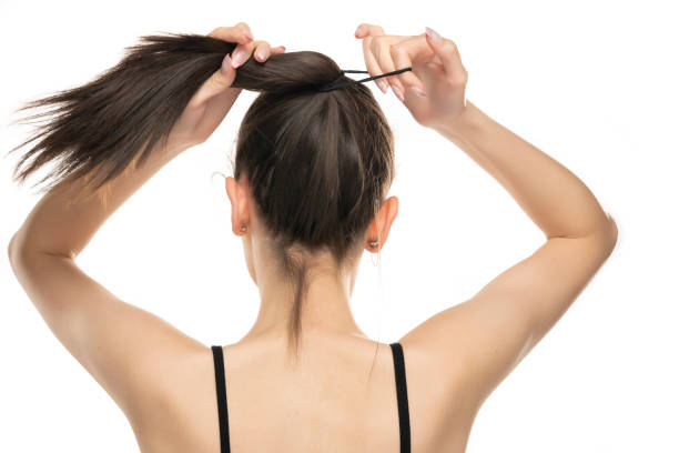 Rear view of a young woman tying her long hair Rear view of a young woman tying her long hair on white background in bounds stock pictures, royalty-free photos & images