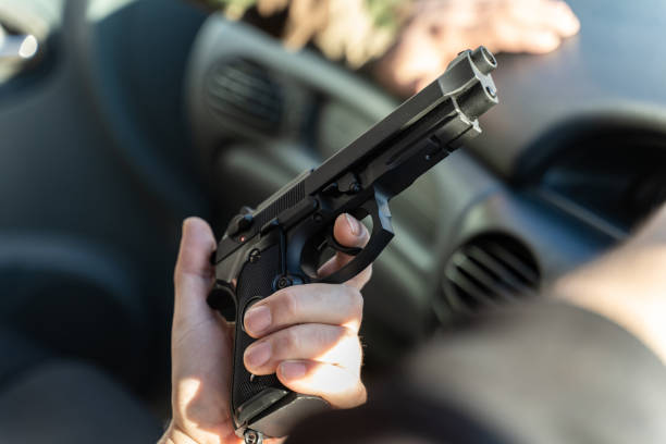 nahaufnahme der hand eines unbekannten kaukasischen mannes, der eine waffe im auto hält - bodyguard holding gun 20s stock-fotos und bilder